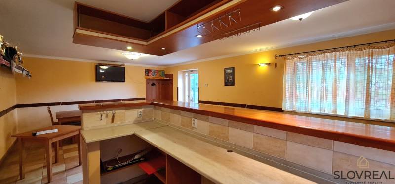 Predaj Domu v obci Lovča - Interiér rodinného domu s barom, dreveným nábytkom a televíziou, svetlý priestor.