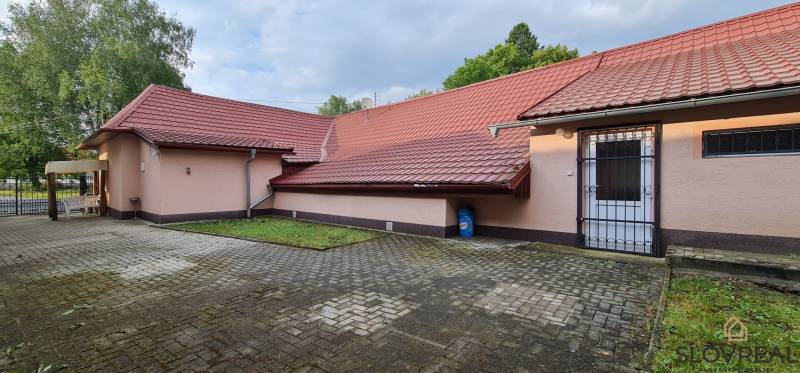 Predaj Domu v obci Lovča - Rodinný dom v Lovči s dlaždeným dvorom a červenou strechou.