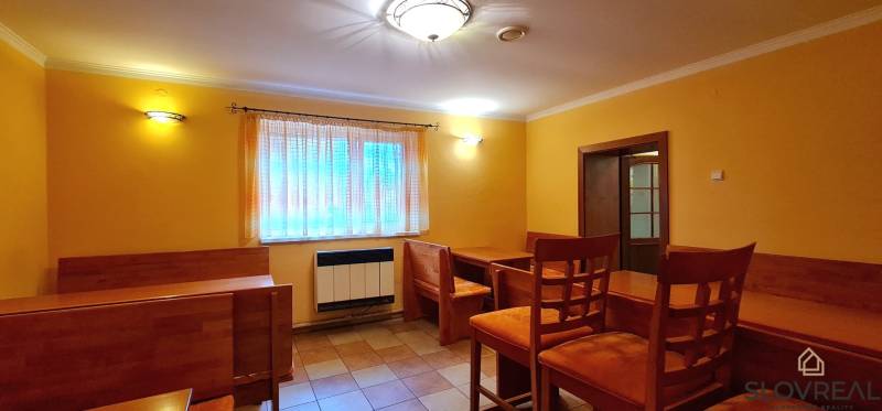 Predaj Domu v obci Lovča - Jasne osvetlený interiér rodinného domu s dreveným nábytkom a oranžovými stenami.