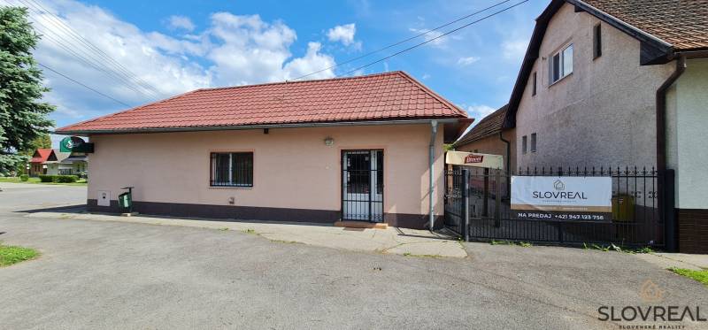 Predaj Domu v obci Lovča - Rodinný dom v Lovči so šikmou červenou strechou a reklamnou tabuľou na predaj.