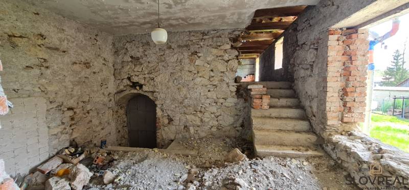 Na predaj dom Lutila, 713 m2 - Kamenné steny rodinného domu s nedokončenými schodiskami a oknami na ulici Nová.