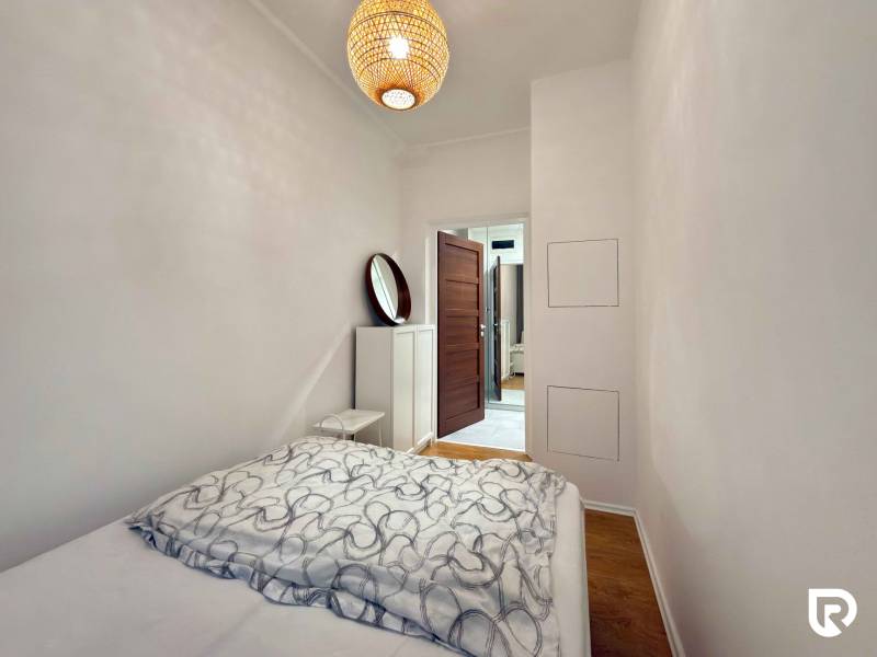 2-izbový byt 45m2 | Sklenárová - Ružinov - Spálňa s posteľou a podlahou s dreveným dekorom v 2-izbovom byte.