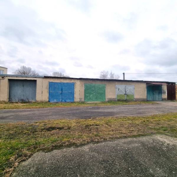 Predaj 3 - izbového bytu v Kuklove !!! - Budova so sériou pestrých garážových brán v Kuklove, vedľa asfaltovej cesty.