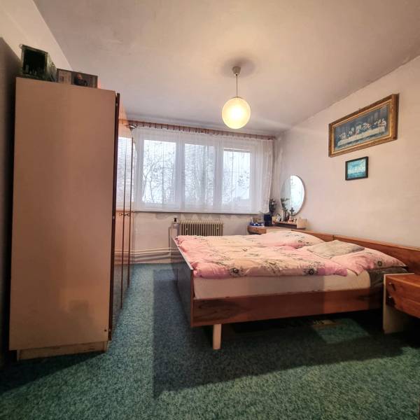 Predaj 3 - izbového bytu v Kuklove !!! - Spálňa v 3-izbovom byte s dvojposteľou, koberec, nábytok a záclony na okne.