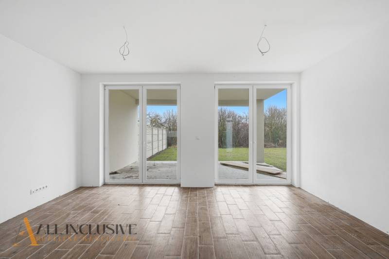 Na predaj 4-izbové novostavby, Veľká Paka - V Rodinnom dome je priestranná miestnosť s veľkými oknami a podlahou s dreveným dekorom.