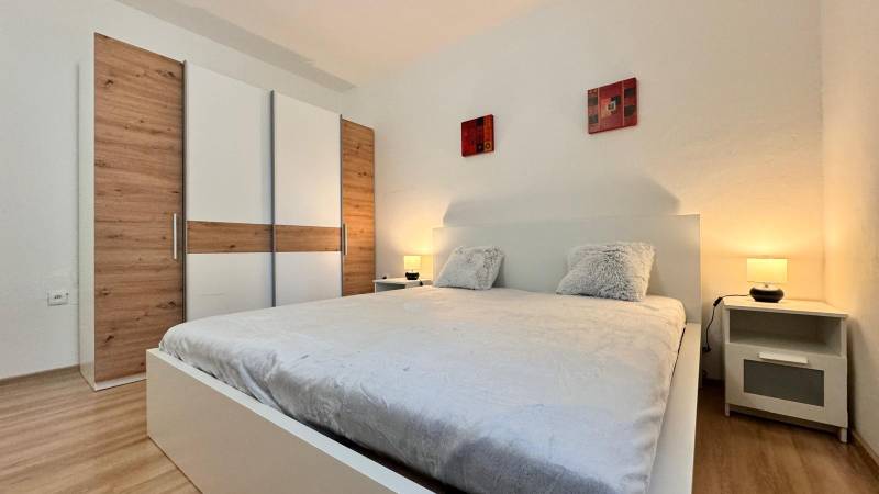 Prenájom 2 izbový byt Trenčín s vlastným parkovaním a terasou - Spálňa v 2-izbovom byte s veľkou posteľou, šatníkovou skriňou a podlahou s dreveným dekorom.