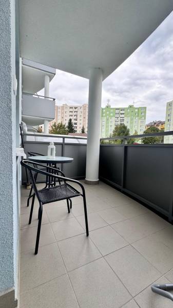 Prenájom 2 izbový byt Trenčín s vlastným parkovaním a terasou - Balkón 2-izbového bytu na Halalovke v Trenčíne so stolom a stoličkami, výhľad na paneláky.