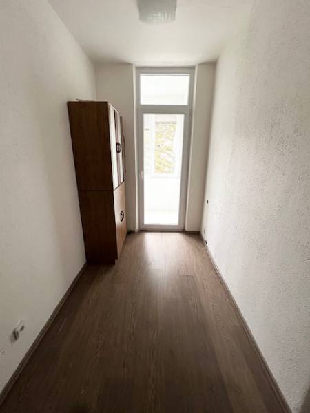 Ponuka na prenájom 2,5 izbový byt Zl. Potok - Úzky interiér 2-izbového bytu s podlahou s dreveným dekorom a skrinkou.