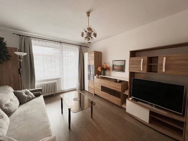 Ponuka na prenájom 2,5 izbový byt Zl. Potok - Obývacia izba v 2-izbovom byte s podlahou s dreveným dekorom, elegantným nábytkom a televízorom.