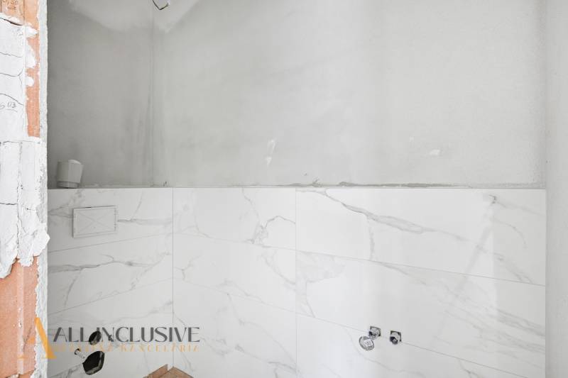 Na predaj 4-izbové novostavby, Veľká Paka - Kúpeľňa v rodinnom dome s bielymi mramorovými obkladmi bez zariaďovacích predmetov.