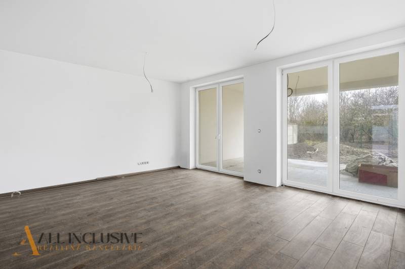 Na predaj 4-izbové novostavby, Veľká Paka - Priestranná izba v rodinnom dome s veľkými oknami a podlahou s dreveným dekorom.