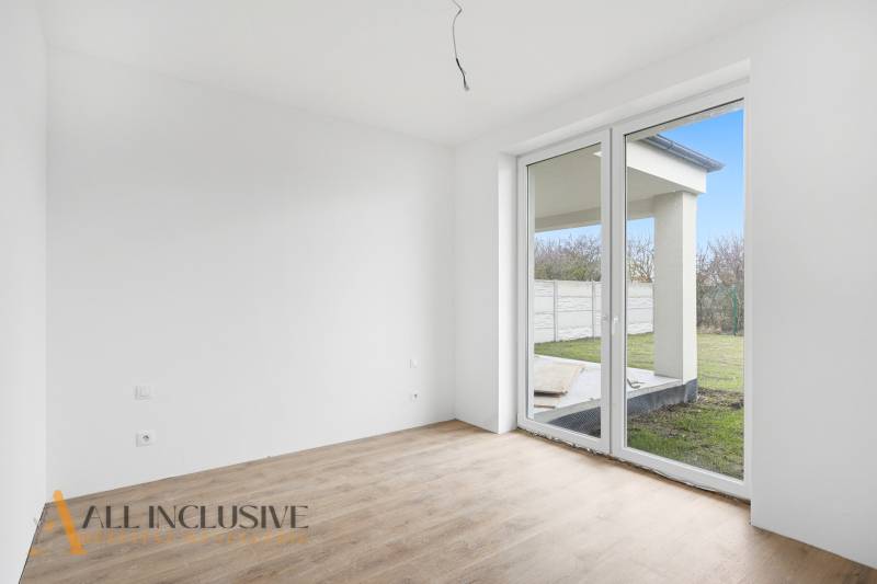 Na predaj 4-izbové novostavby, Veľká Paka - Izba v rodinnom dome s veľkým oknom a podlahou s dreveným dekorom.