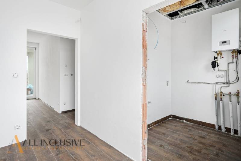 Na predaj 4-izbové novostavby, Veľká Paka - Interiér rodinného domu s podlahou s dreveným dekorom a vykurovacím zariadením.