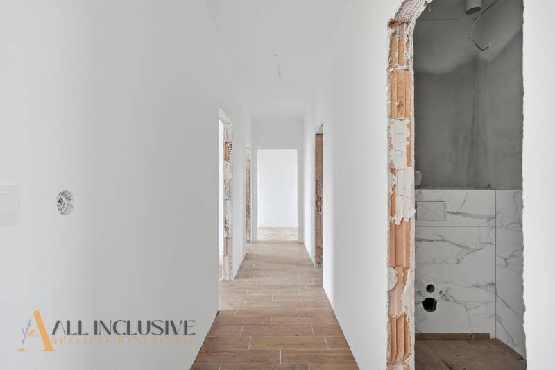 Na predaj 4-izbové novostavby, Veľká Paka - Chodba v rodinnom dome s bielymi stenami a podlahou s dreveným dekorom.