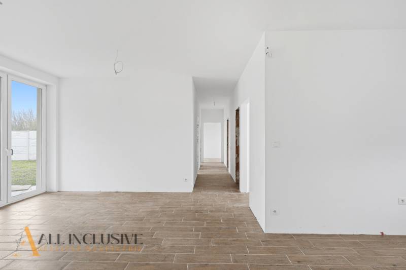 Na predaj 4-izbové novostavby, Veľká Paka - Biela chodba v rodinnom dome s podlahou s dreveným dekorom a presklenými dverami do dvora.