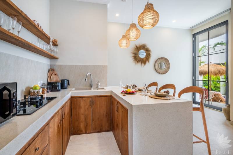 LUXUSNÁ 3-SPÁLŇOVÁ VILA S BAZÉNOM – CANGGU, BALI - Interiér vily s kuchynským kútom, drevenými skrinkami a dekoratívnymi zrkadlami.