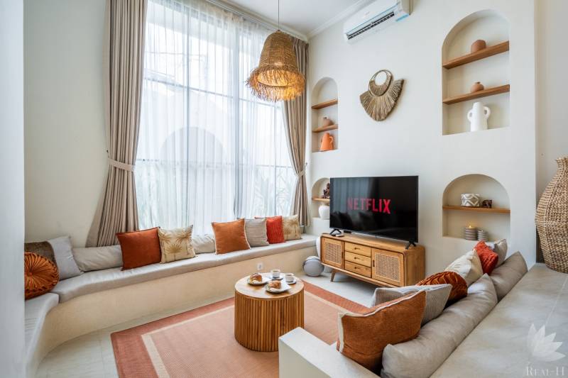 LUXUSNÁ 3-SPÁLŇOVÁ VILA S BAZÉNOM – CANGGU, BALI - Svetlý obývací priestor vo Vile s pohovkou, TV a dekoratívnym osvetlením.