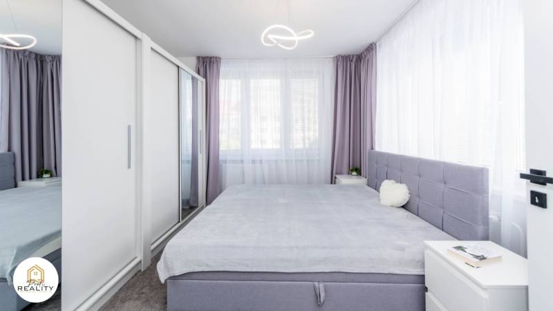 PRENÁJOM | 3i byt v centre Prešova | ZARIADENÝ - Svetlá spálňa s veľkou posteľou, vstavanou skriňou a fialovými závesmi v 3-izbovom byte.