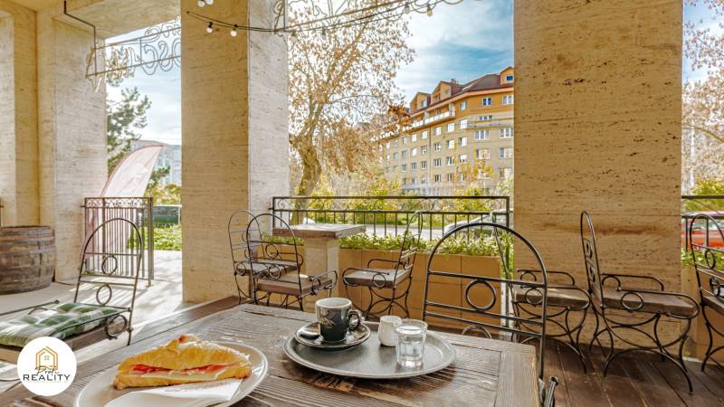 PRENÁJOM | 3i byt v centre Prešova | ZARIADENÝ - V exteriéri Pavlovičovho námestia v Prešove káva a sendvič na stole, výhľad na budovy.