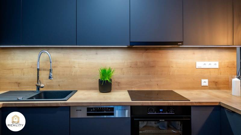 PRENÁJOM | 3i byt v centre Prešova | ZARIADENÝ - Kuchynská linka s tmavými úložnými skrinkami a podlahou s dreveným dekorom.