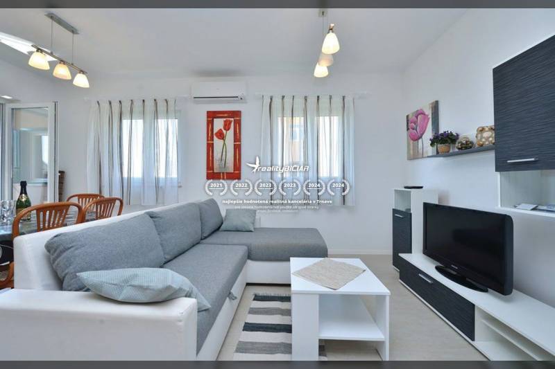 PRIVLAKA - BYT S4- dvojizbový byt 63,42 m2 vzdialený 150 m od mora - Obývačka v 2-izbovom byte s pohodlným gaučom, bielym nábytkom a televízorom.