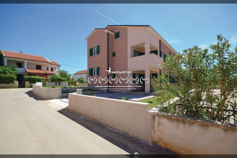 PRIVLAKA - BYT S4- dvojizbový byt 63,42 m2 vzdialený 150 m od mora - 2-izbový byt na ulici Privlaka v Privlake, obklopený zelenými kríkmi a susednými domami.