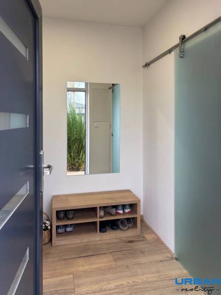 Moderný 3-izbový byt so záhradou Šamorín-Kráľovianky - 3-izbový byt s lavicou na topánky, zrkadlom a podlahou s dreveným dekorom.