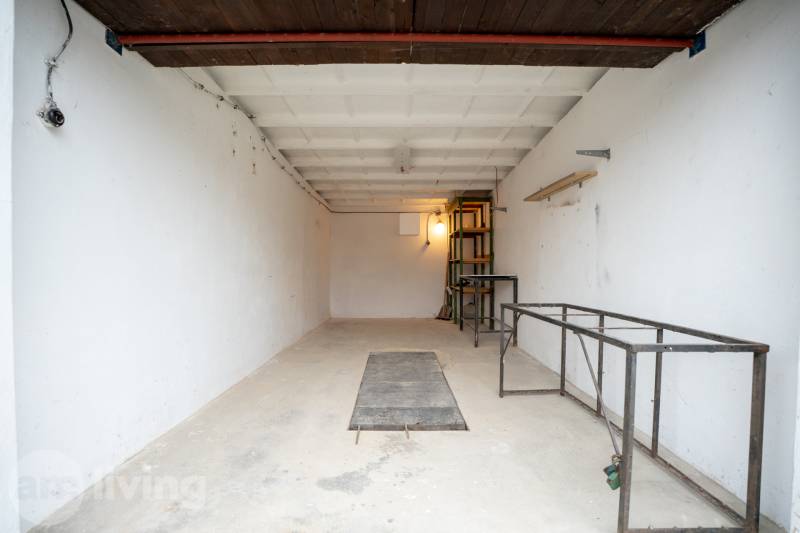 TOP LOKALITA - Garáž na predaj - Trenčín - Priestranný interiér Garáže s kovovými policami a bielymi stenami.