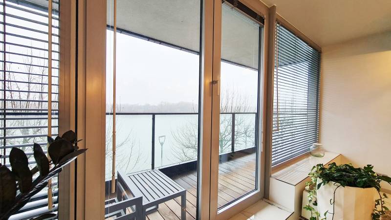 Luxusný 3-izb. byt s famóznym výhľadom na Dunaj, River Park - Balkón s výhľadom na rieku, sklenené dvere, podlaha s dreveným dekorom.