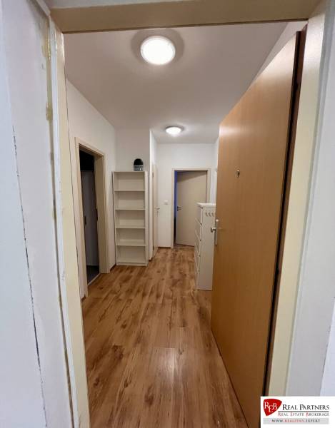 Prenájom 2-izb bytu Dlhé diely - Chodba v 2-izbovom byte s podlahou s dreveným dekorom a poličkami na stene.