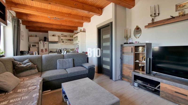 Praktický 8-izbový rodinný dom na Bystričke: Vhodný pre veľkú rodinu z - Obývacia izba v rodinnom dome s pohovkou, kuchyňou a podlahou s dreveným dekorom.