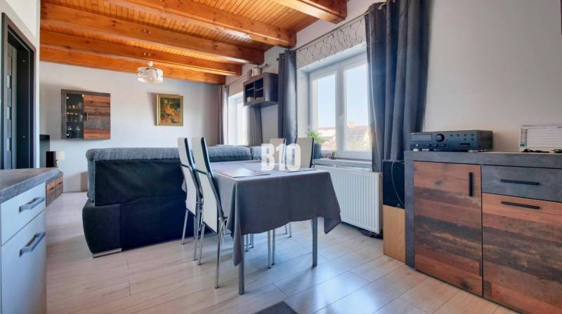 Praktický 8-izbový rodinný dom na Bystričke: Vhodný pre veľkú rodinu z - Interiér rodinného domu s podlahou s dreveným dekorom a stolom pri okne.