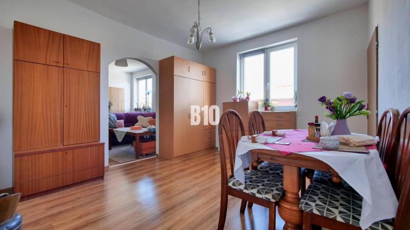 Praktický 8-izbový rodinný dom na Bystričke: Vhodný pre veľkú rodinu z - Jedáleň v rodinnom dome s nábytkom, podlahou s dreveným dekorom a stolom s kvetmi.