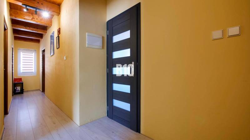 Praktický 8-izbový rodinný dom na Bystričke: Vhodný pre veľkú rodinu z - Chodba v rodinnom dome s podlahou s dreveným dekorom a dreveným stropom.