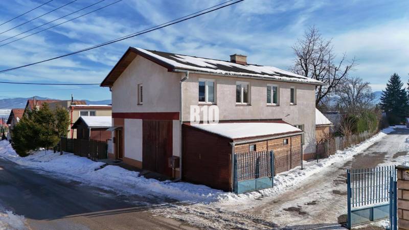 Praktický 8-izbový rodinný dom na Bystričke: Vhodný pre veľkú rodinu z - Rodinný dom v Bystričke počas zimy so snehom na streche a ceste.