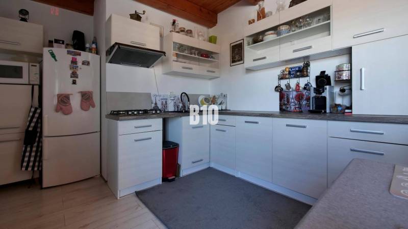 Praktický 8-izbový rodinný dom na Bystričke: Vhodný pre veľkú rodinu z - Kuchyňa v rodinnom dome so svetlými skrinkami, mikrovlnkou a kávovarom.