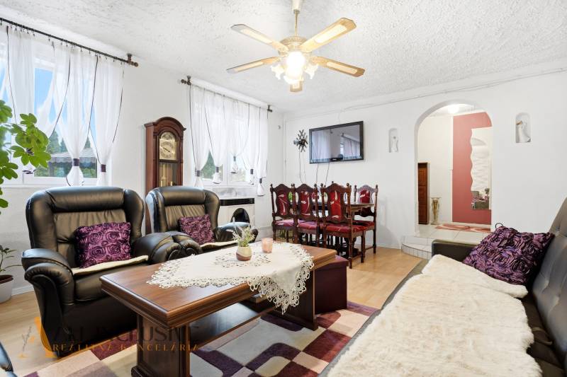 REZERVOVANÉ 4-izb. rodinný dom s garážou, Čierny Brod - Obývacia izba Rodinného domu s kozubom, čiernymi sedačkami a podlahou s dreveným dekorom.