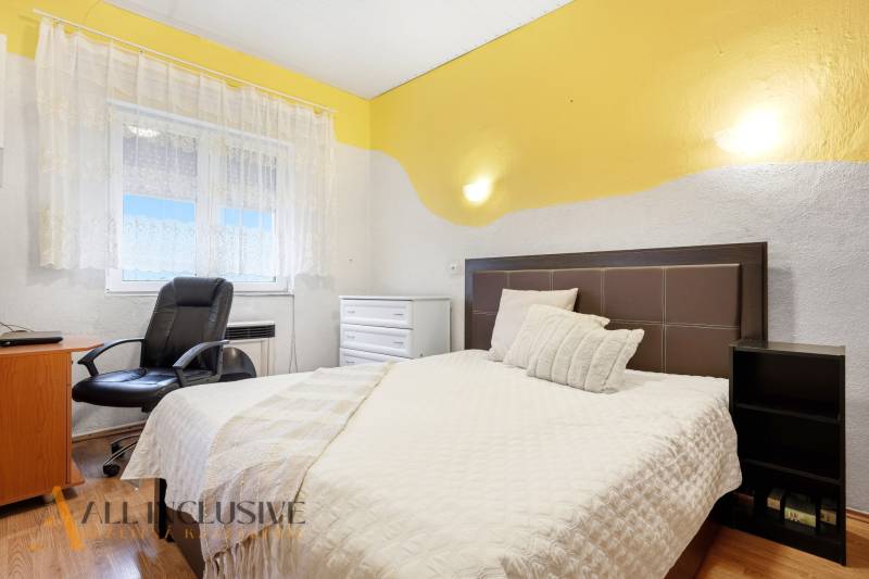 REZERVOVANÉ 4-izb. rodinný dom s garážou, Čierny Brod - Spálňa v rodinnom dome s posteľou, kreslom a podlahou s dreveným dekorom.