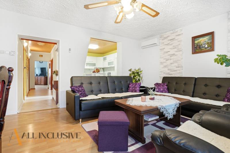 REZERVOVANÉ 4-izb. rodinný dom s garážou, Čierny Brod - Obývacia izba v rodinnom dome s podlahou s dreveným dekorom a čiernymi koženými sedačkami.