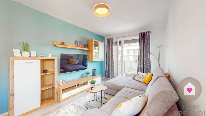 BA/PETRŽALKA-Prenájom moderného 3i bytu s parkovacím státim-Slnečnice - Obývacia izba v 3-izbovom byte s pohodlnou sedačkou a balkónom, podlaha s dreveným dekorom.