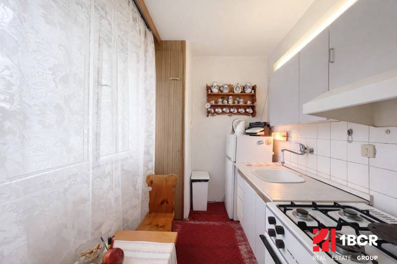 NA PREDAJ 1-IZBOVÝ BYT V PÔVODNOM STAVE – DÚBRAVKA, SARATOVSKÁ ULICA - Útulná kuchyňa s plynovým sporákom a rustikálnou dekoráciou v 1-izbovom byte.