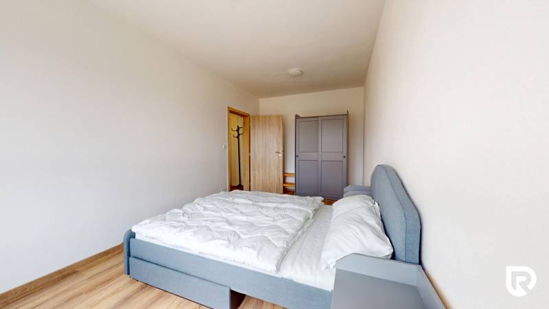 | 3-izbový byt v novostavbe, ul. Odevná + parking | Trenčín  - Spálňa v 3-izbovom byte s posteľou, šatníkom a podlahou s dreveným dekorom.