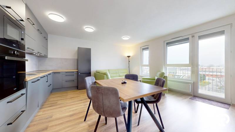 | 3-izbový byt v novostavbe, ul. Odevná + parking | Trenčín  - Kuchyňa s podlahou s dreveným dekorom a jedálenským stolom v 3-izbovom byte.