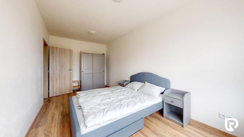 | 3-izbový byt v novostavbe, ul. Odevná + parking | Trenčín  - Spálňa v 3-izbovom byte s podlahou s dreveným dekorom, sivou posteľou a šatníkom.