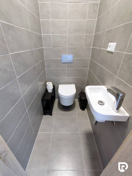 | 3-izbový byt v novostavbe, ul. Odevná + parking | Trenčín  - Kúpeľňa s nástennou toaletou, umývadlom a sivými obkladačkami v 3-izbovom byte.