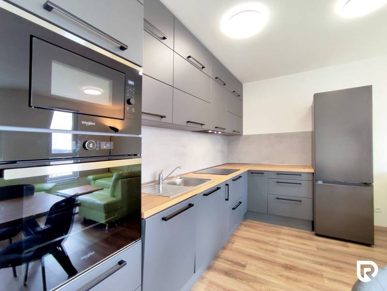 | 3-izbový byt v novostavbe, ul. Odevná + parking | Trenčín  - Kuchyňa v 3-izbovom byte s podlahou s dreveným dekorom, šedé skrinky, vstavané spotrebiče.