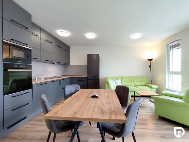 | 3-izbový byt v novostavbe, ul. Odevná + parking | Trenčín  - Svetlá kuchyňa s jedálenským stolom a pohovkou v 3-izbovom byte s podlahou s dreveným dekorom.
