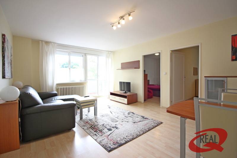 **PREDAJ 3-IZBOVÉHO BYTU S BALKÓNOM A LOGGIOU PRI SLUBEKOVEJ ZÁHRADE** - Obývačka 3-izbového bytu s pohovkou, stolíkom a televíziou na podlahe s dreveným dekorom.