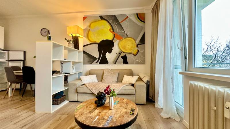 – PRENAJOM – 2 IZBOVÝ BYT 52 m² – OSTREDKOVA – RUŽINOV  - Obývačka v 2-izbovom byte s pohovkou, obrazom a podlahou s dreveným dekorom.