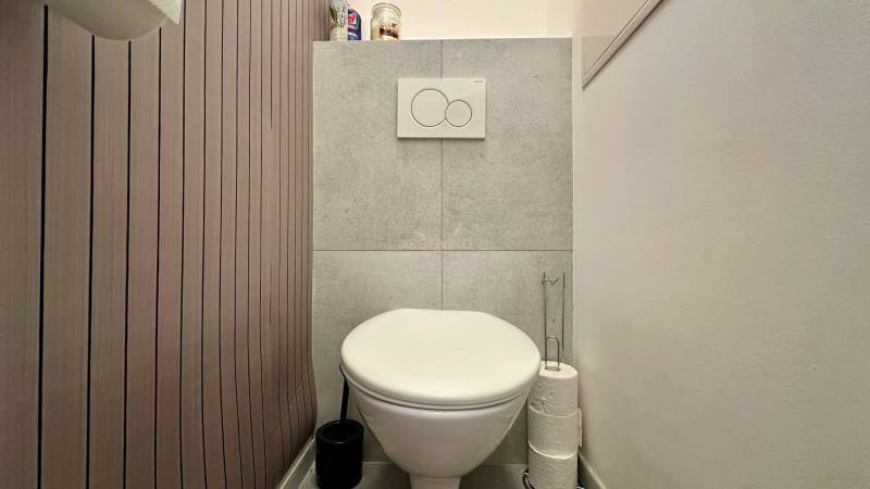 – PRENAJOM – 2 IZBOVÝ BYT 52 m² – OSTREDKOVA – RUŽINOV  - Toaleta v 2-izbovom byte s obkladom v drevenom dekore a úložným priestorom.